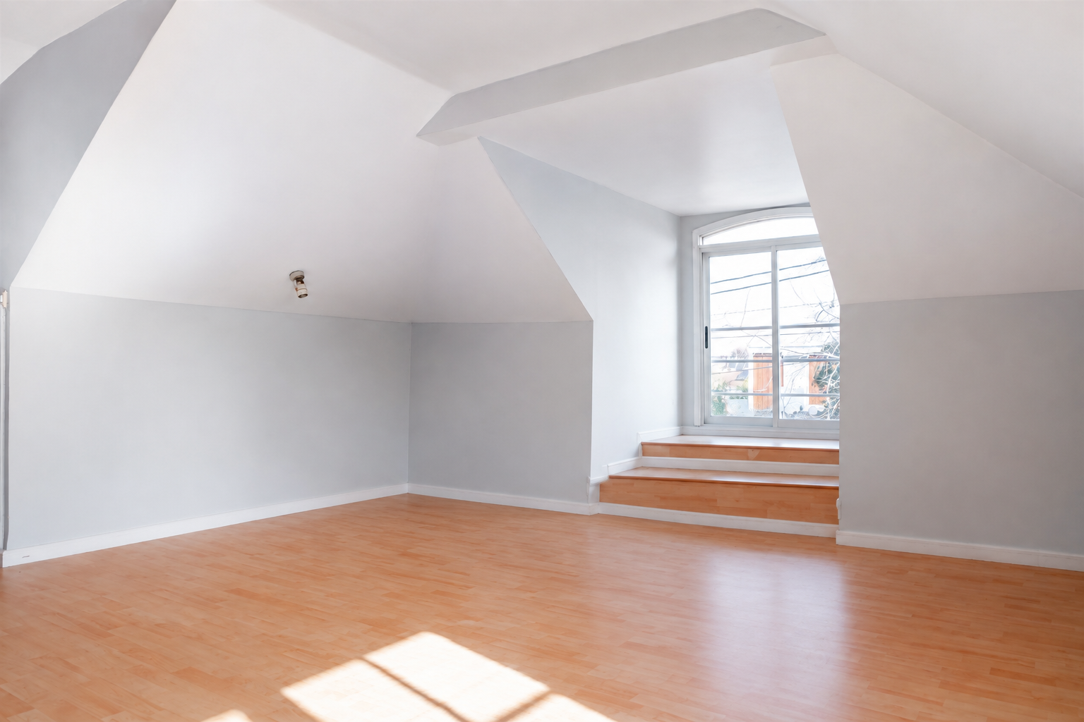 Dormitorio abuhardillado vacío antes del home staging, con piso de madera y muro inclinado